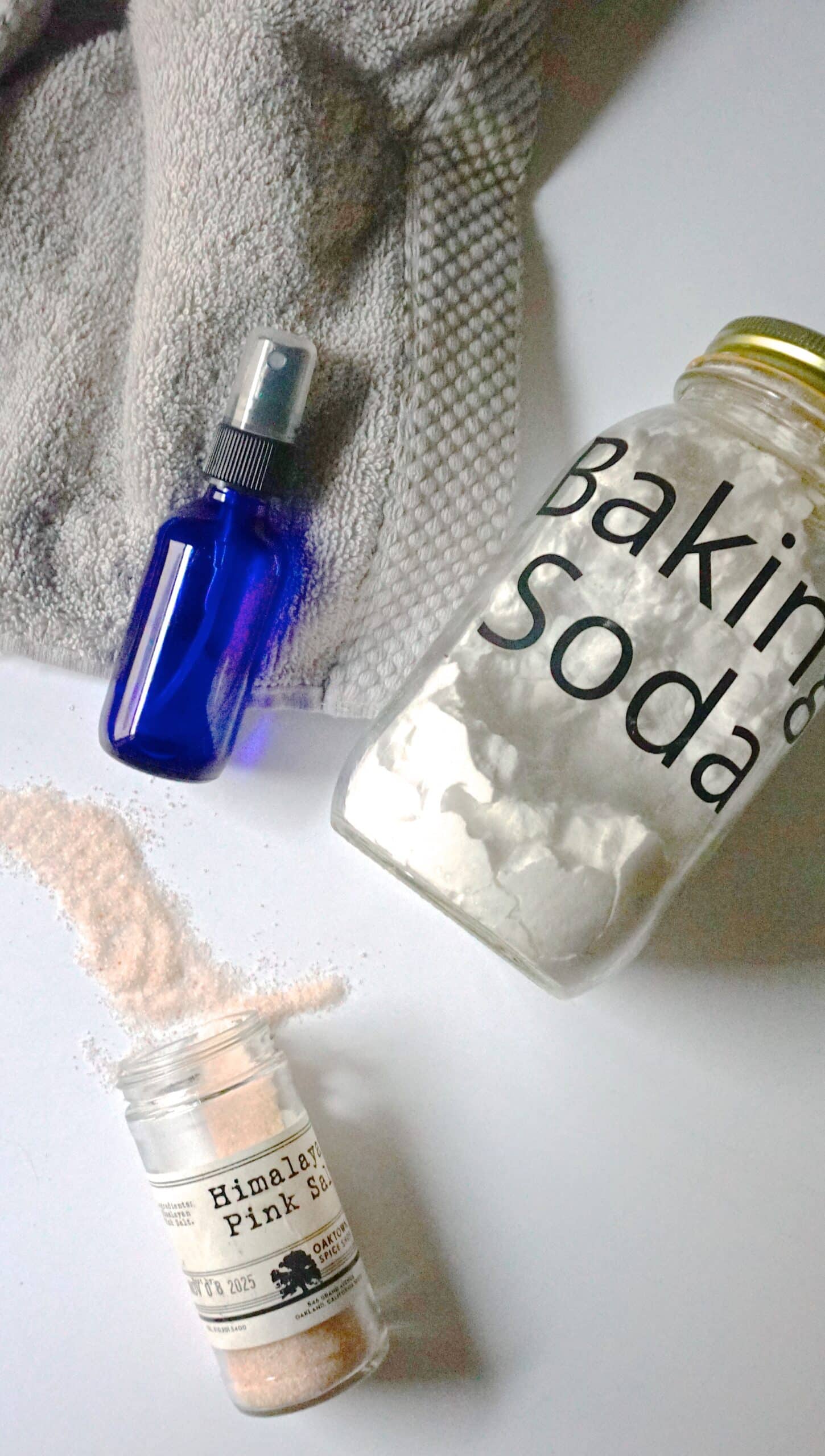 overhead image of a spray bottle, jar of baking soda, and pink Himalayan salt