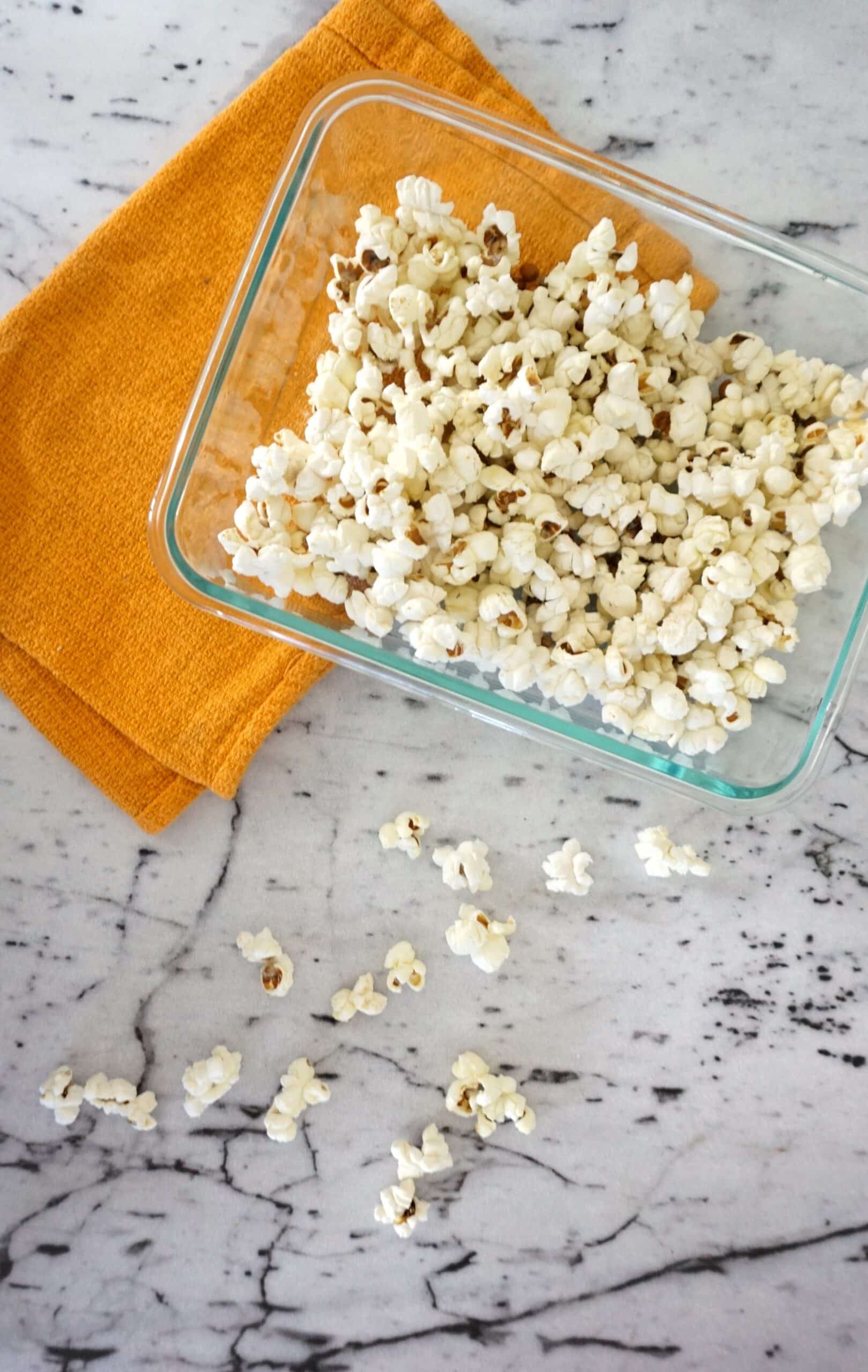 overhead: a glass dish full of popcorn on an orange towel