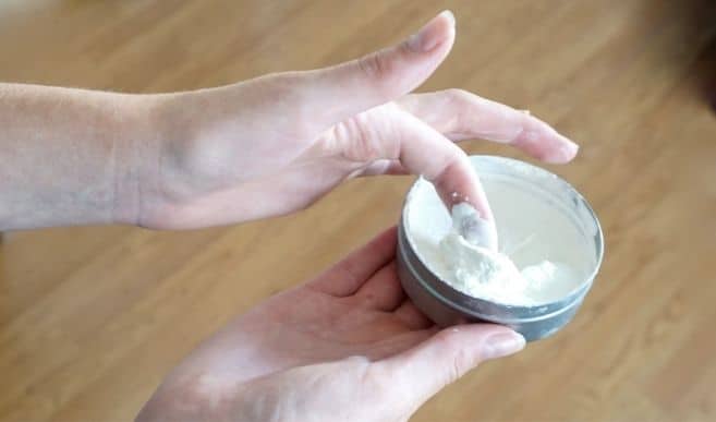 finger lifting mineral sunscreen out of container