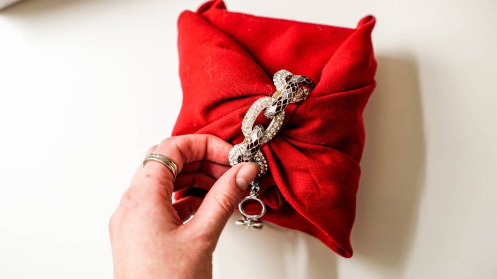 A cloth napkin gift wrap secured with a bracelet to show how to wrap a gift without tape