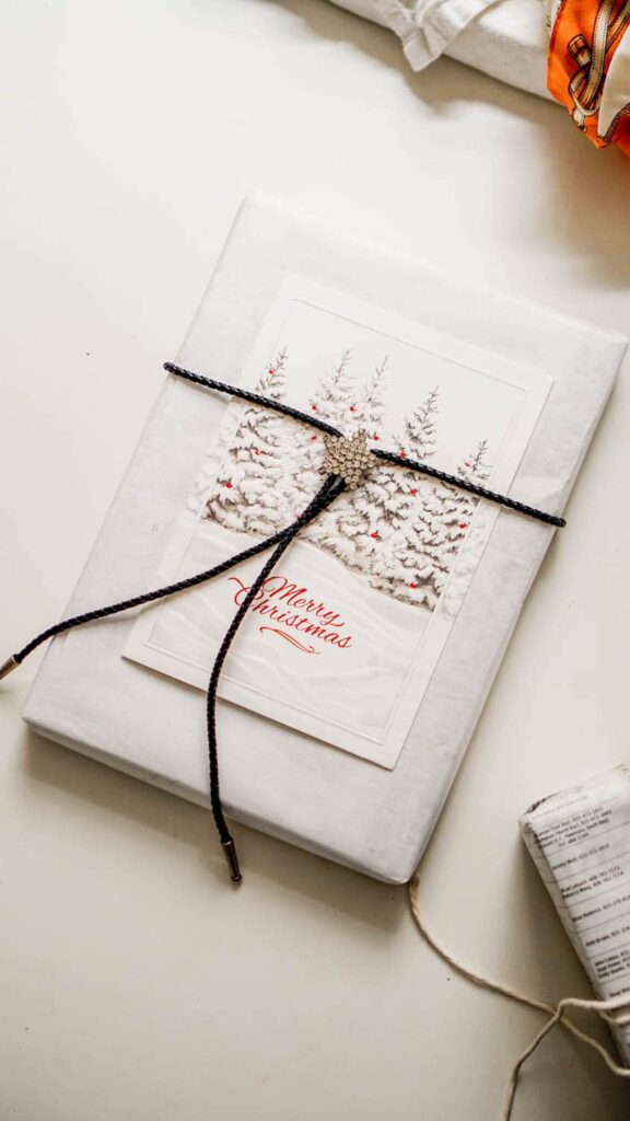 A gift with a card secured to it with a lariat to illustrate how to wrap a gift without tape.