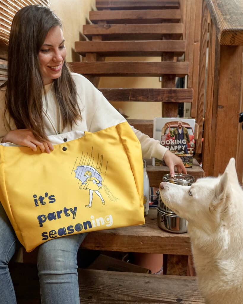 Kathryn with a bag, an insulated container, and a cookbook to illustrate Thanksgiving leftover ideas.