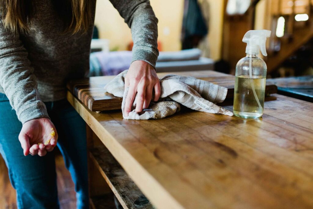 image of a woman using a reusable rag and non-toxic spray for cleaning