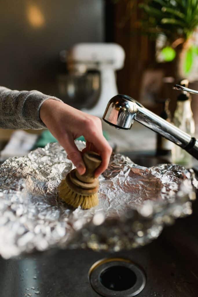 image of a compostable dish scrub being used to clean foil