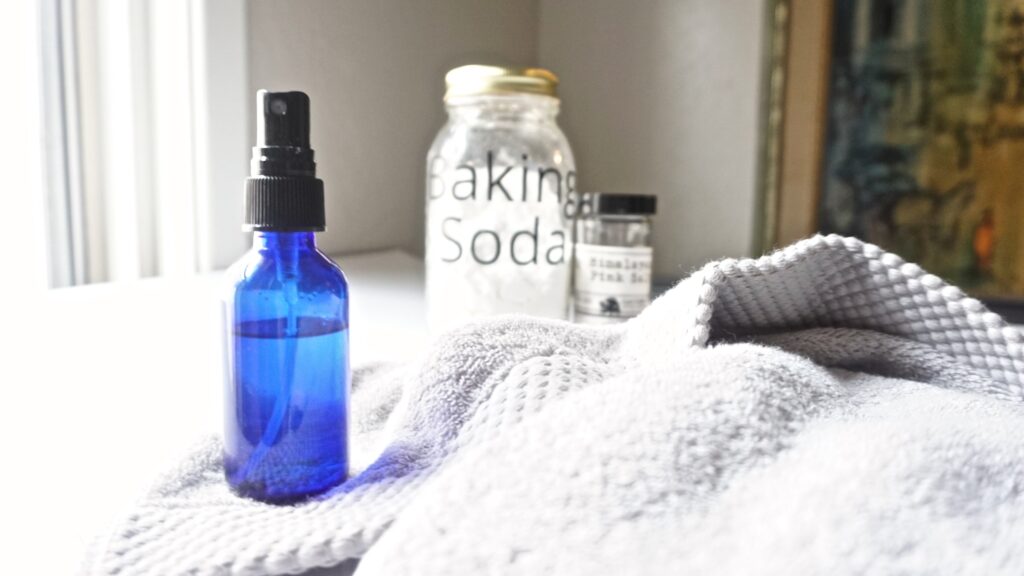 image of a spray bottle in front, and a jar of baking soda and pink Himalayan salt in the background