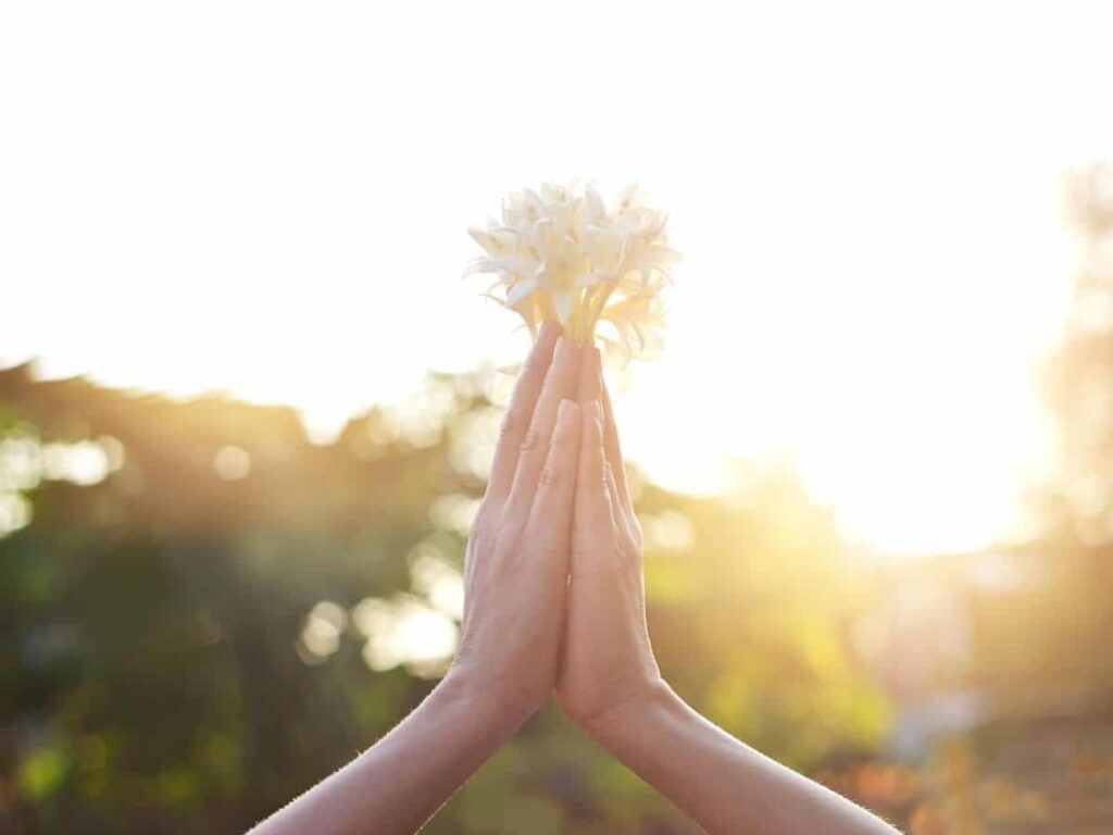 How to forgive yourself: a woman's hands held together in a prayer pose while holding flowers