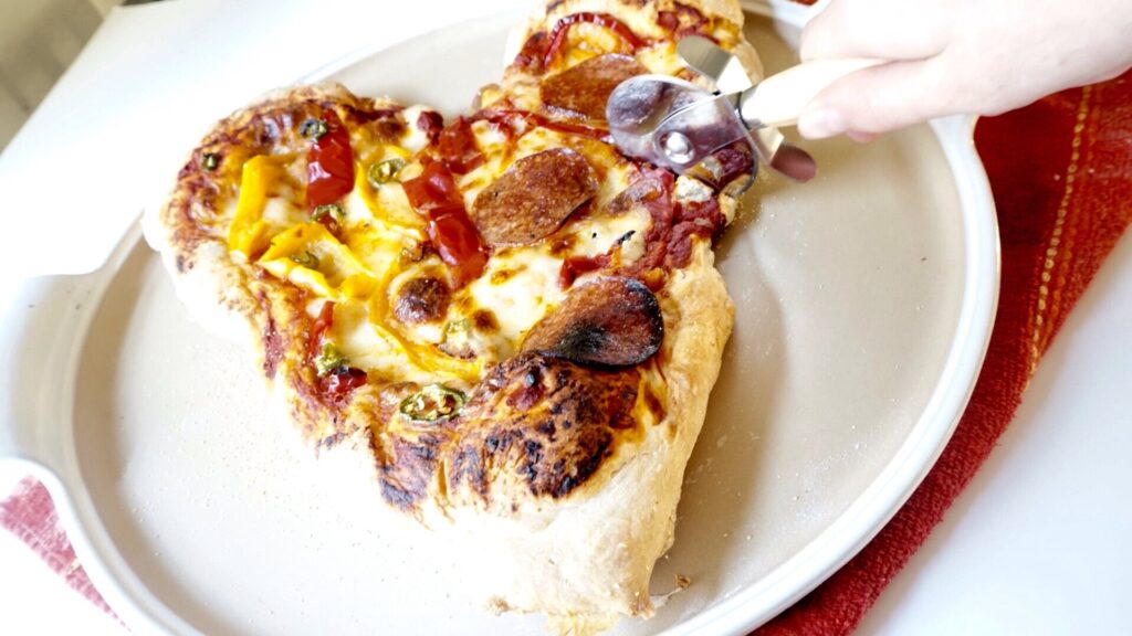 pizza made with quick and easy pizza dough being sliced with a pizza cutter