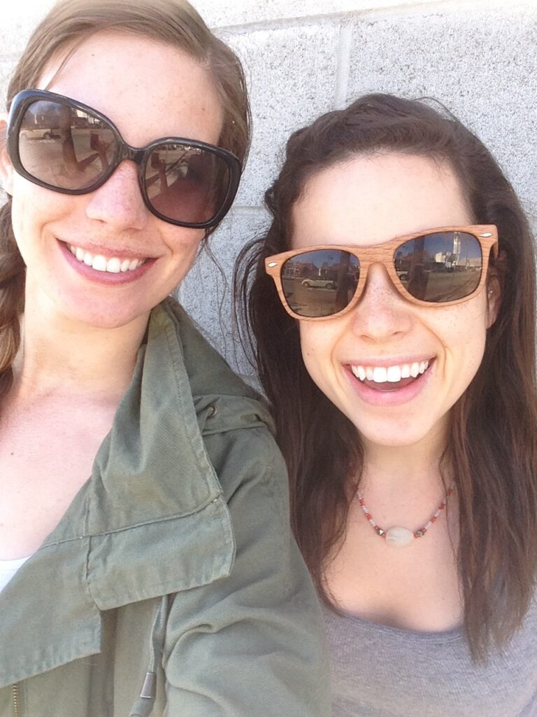 Two women smiling and wearing sunglasses while they travel in a zero waste way