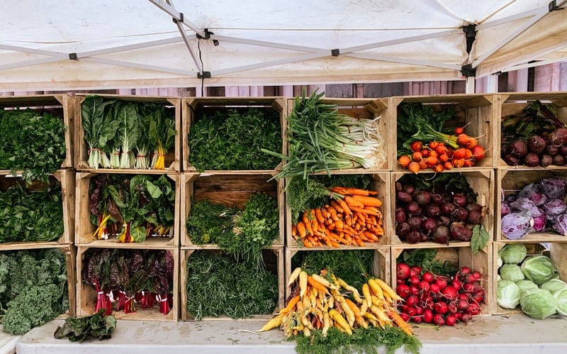 a bunch of different vegetables in crates at a farmer's market