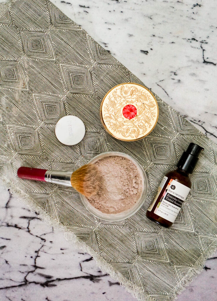 Top view of DIY foundation, tinted moisturizer, and a makeup brush