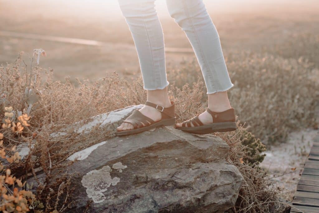 just a woman's legs standing on a rock, wearing shoes from one of these ethical shoe brands.