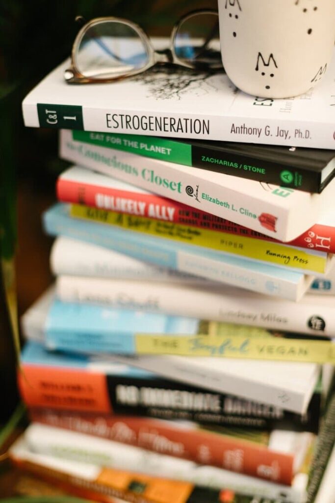 Close up of a stack of the best books on sustainability with a coffee mug and reading glasses on top.