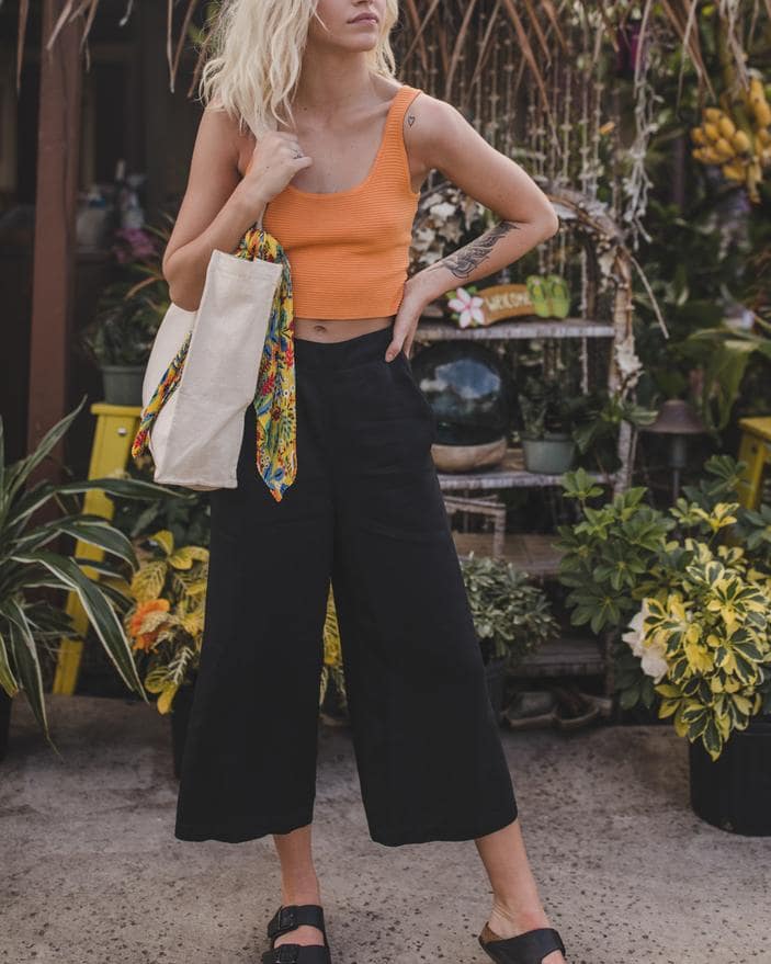 Woman wearing an orange tank and black pants with a tan tote - eco friendly gifts from a small business.