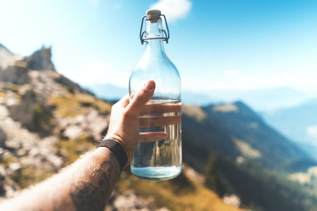 A hand holding a glass water bottle, one of the most eco friendly water bottles