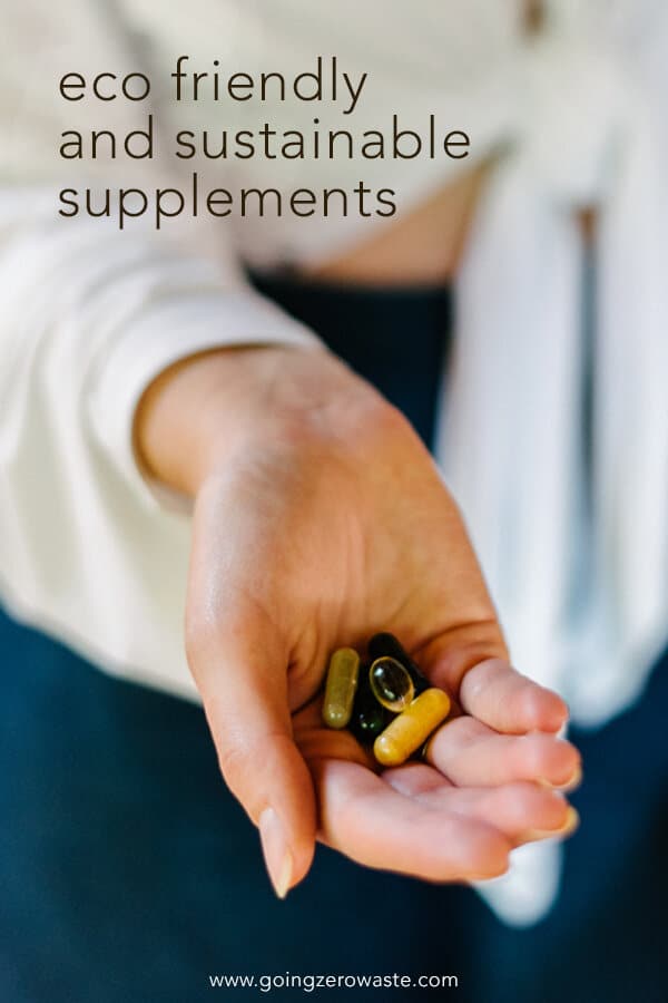 hand holding a handful of supplements from the top brands for vitamins with overlay text reading "eco friendly and sustainable supplements"