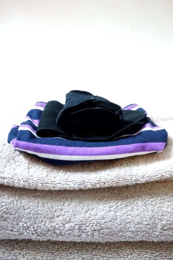 Close up of reusable pads for periods and period panties on top of a stack of towels.
