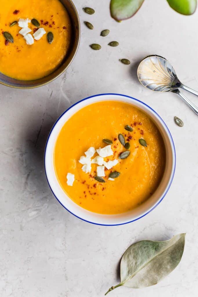 Top view of 2 bowls of pumpkin soup, one of the featured pumpkin puree recipes. 