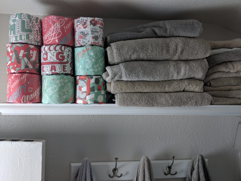 Photo of toilet paper stored with a stack of folded towels in a Who Gives a Crap review post. 