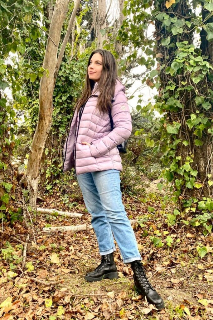 Photo of woman in the forest wearing Bernardo puffer jacket, jeans, and boots.