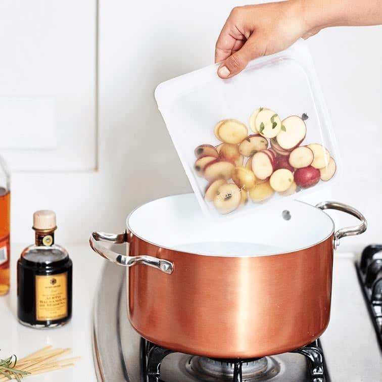 A silicone food bag full of potatoes being placed in a pot of water - a featured item on this list of unique housewarming gift ideas.