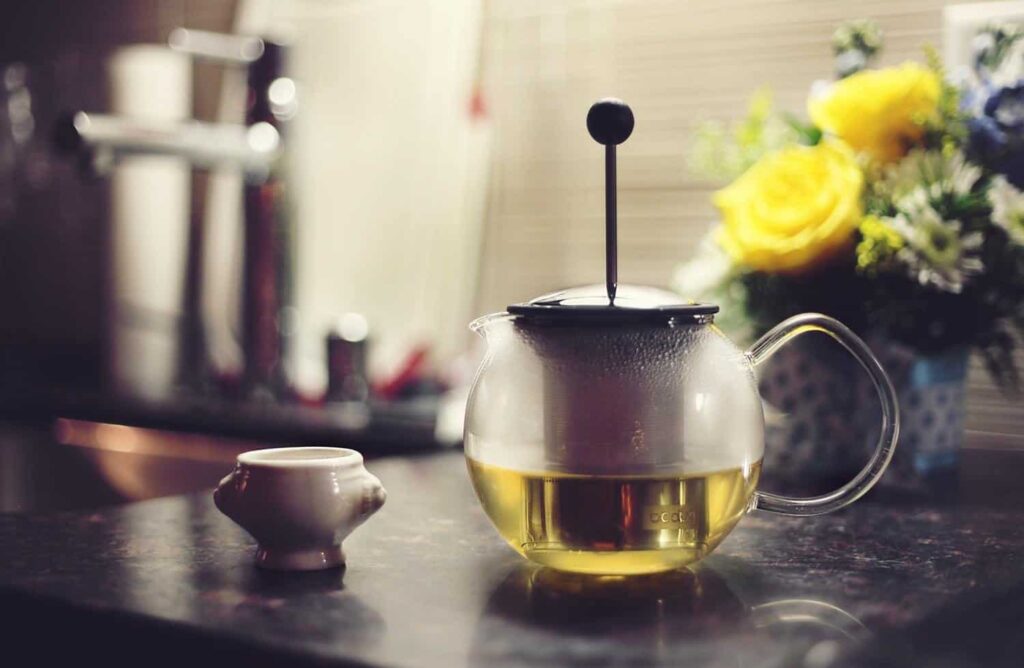 A glass tea kettle with a porcelain teacup to illustrate going plastic free 