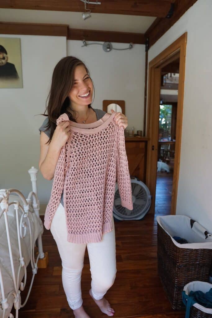 Woman holding up a sweater she found with her second hand shopping tips