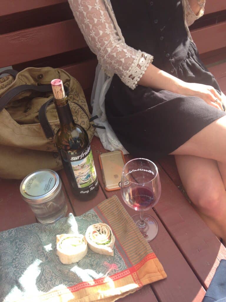 Mason jars as drinking glasses on a picnic with a bottle of wine and vegetable wrap.