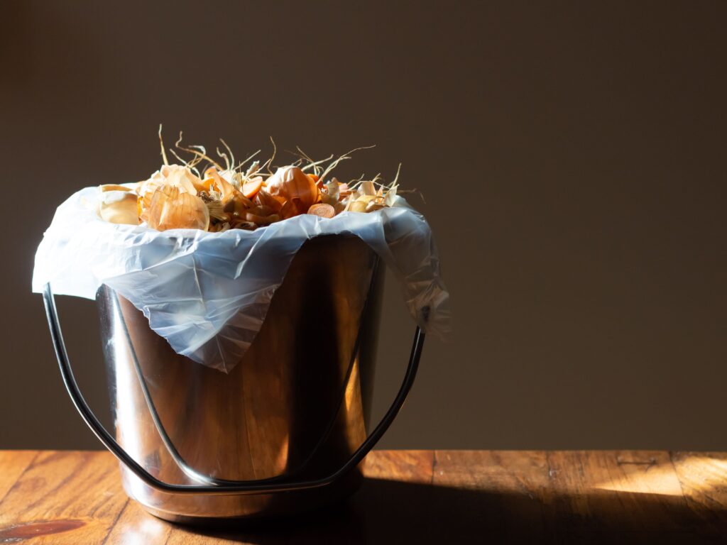 Close up photo of a small compost bin filled with food scraps. 