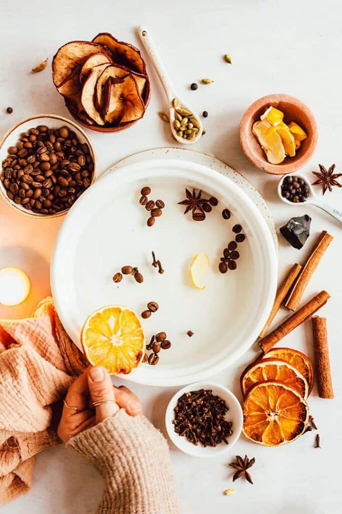 Top view of ingredients needed for a fall simmer pot recipe, including oranges, cinnamon sticks, dried apples, and coffee beans.