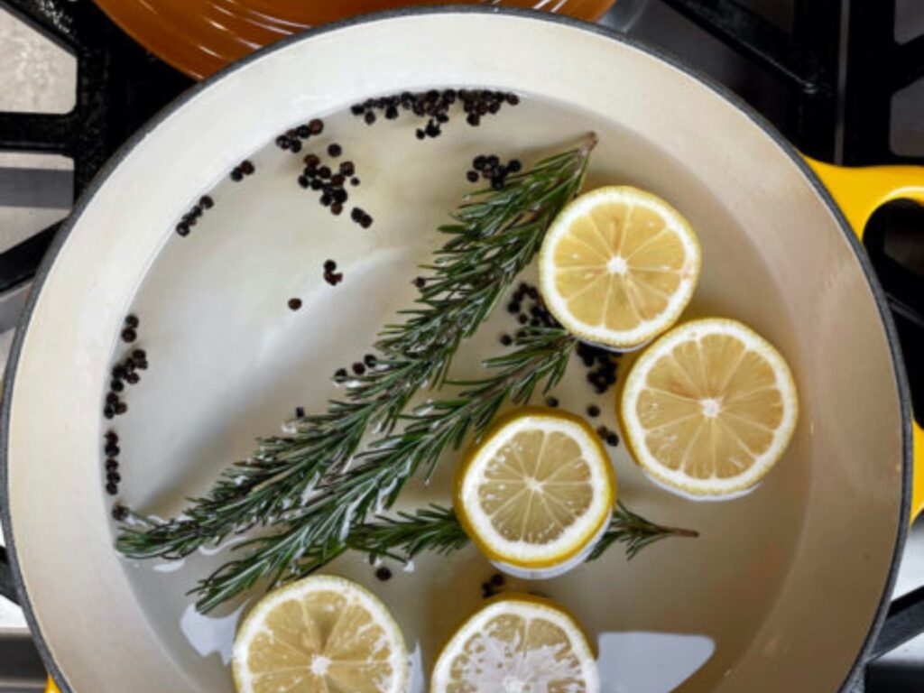 What is a simmer pot? Close up of a pot on a stove with lemon, rosemary, and peppercorns in it.