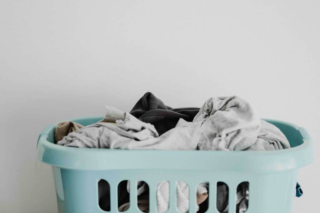 laundry basket filled with clothes to illustrate why you should not wash clothes with DIY laundry detergent 