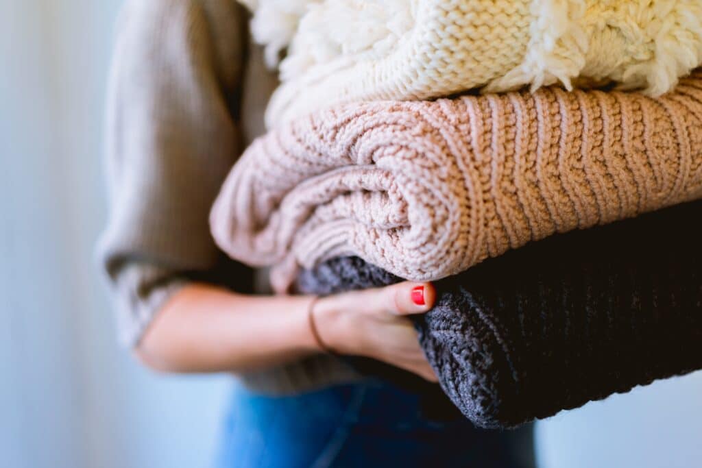 Woman holding a stack of throw blankets washed without fabric softener.. 