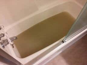 bathtub full of dirty water from stripping clothes of homemade laundry detergent 