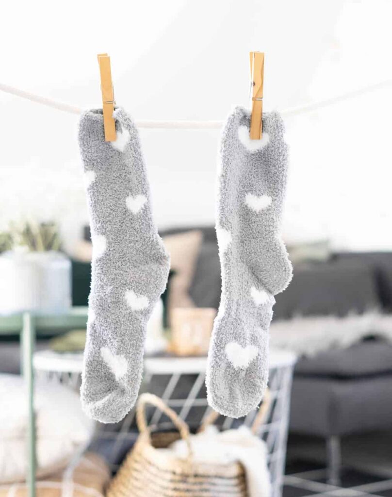 2 gray socks with white hearts on them to illustrate a post about why homemade laundry soap is bad 