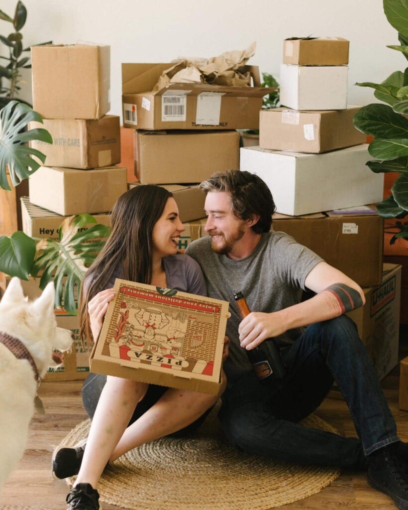 A man and woman sitting in front of a stack of eco friendly moving boxes.