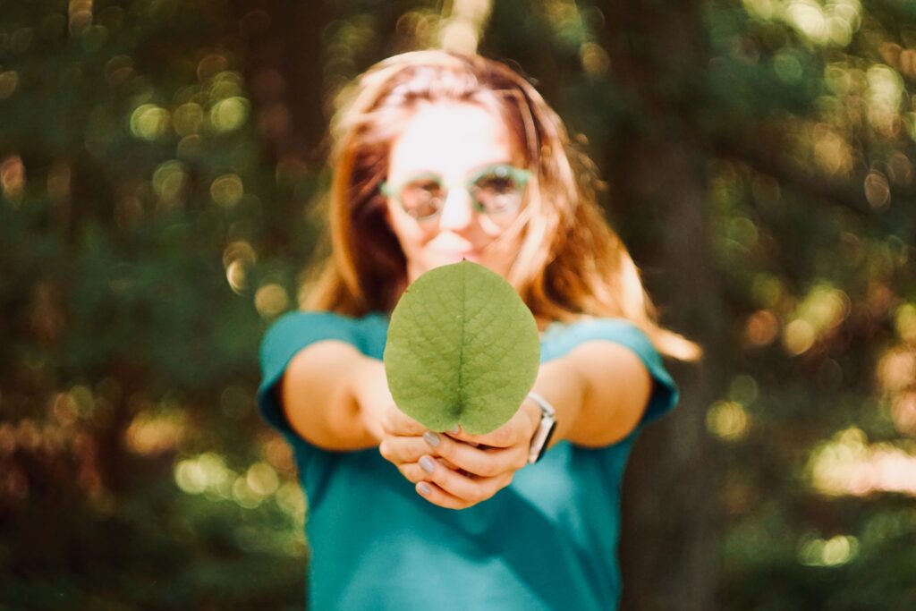 A woman holding a large leaf to illustrate a post about environmental science careers.