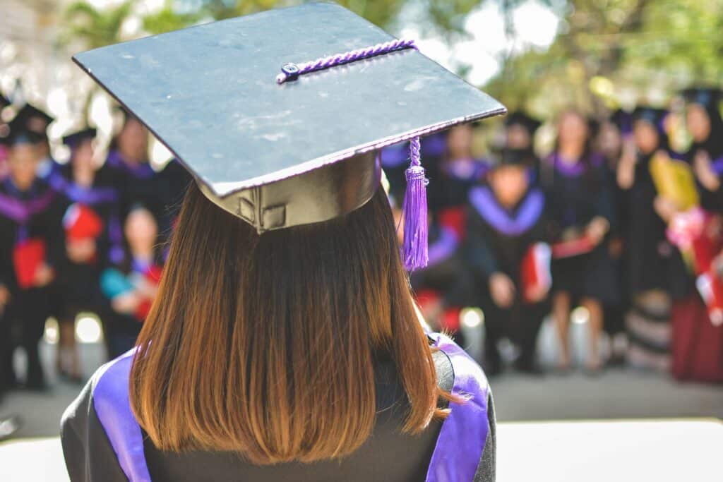 Back of a woman wearing a black and purple cap and gown to illustrate a post about the highest paying jobs with a biology degree