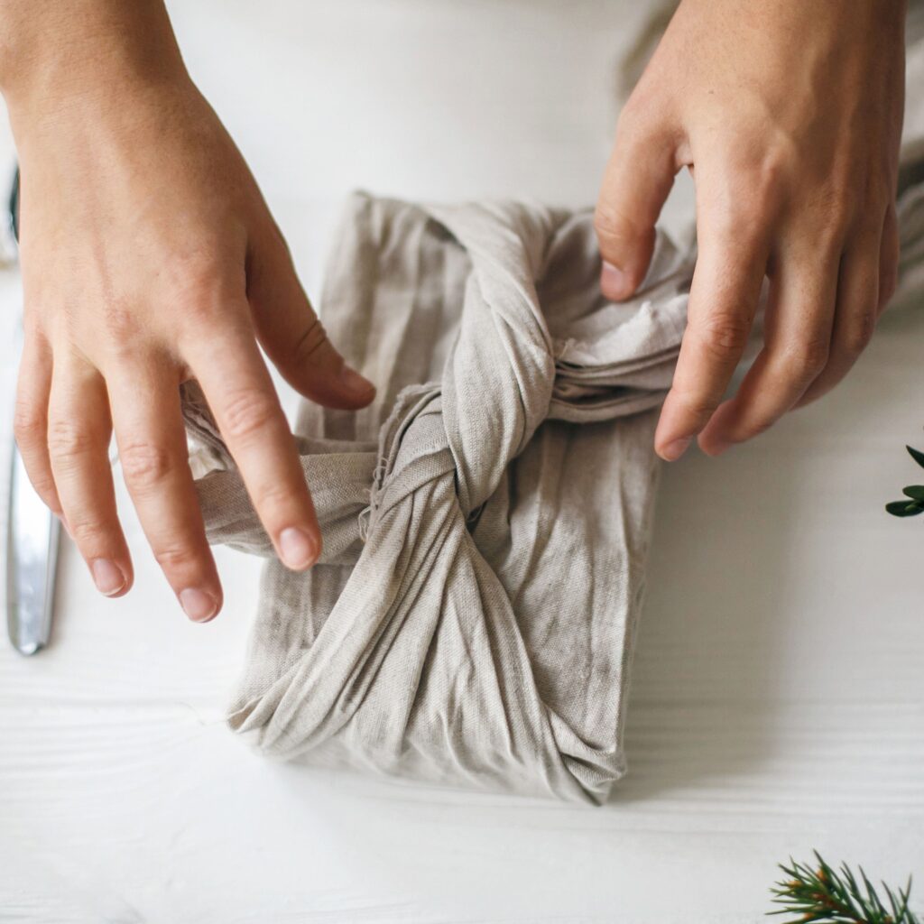 overhead image of hands tying cloth wrapping on a gift
