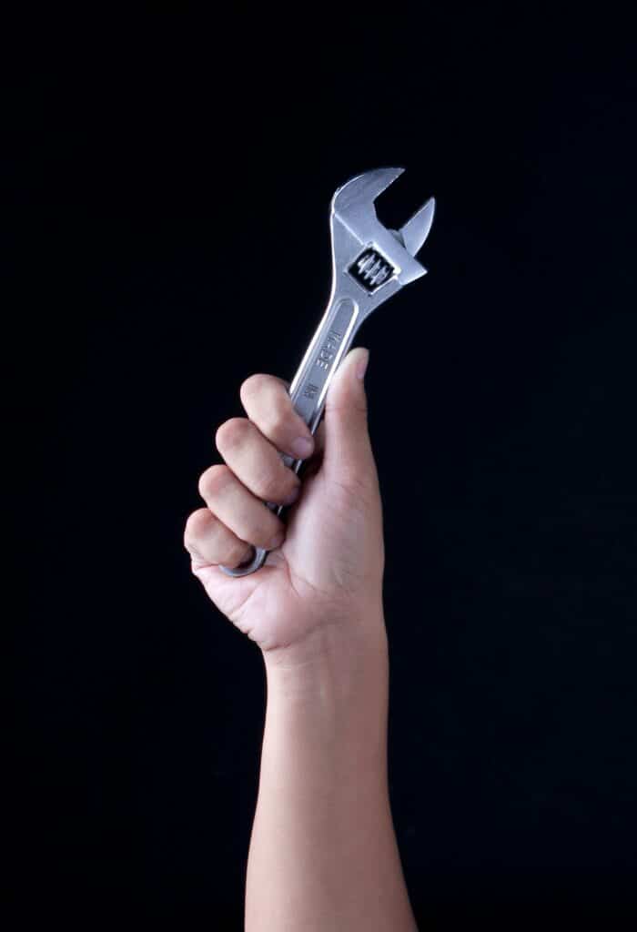 A hand holding a wrench to illustrate a post about how to fix common household items. 