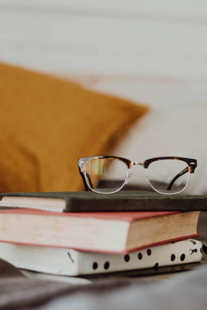 A stack of books with reading glasses on top of it to illustrate sites like Amazon you can buy books from