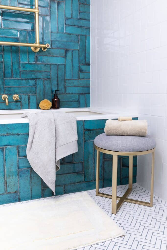 Eco friendly bath towels next to a teal, tiled tub. 