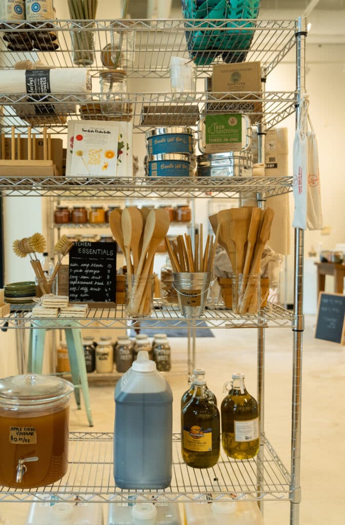 How to start a zero waste store - a close up of a shopping rack in a zero waste store full of sustainable kitchen essentials 