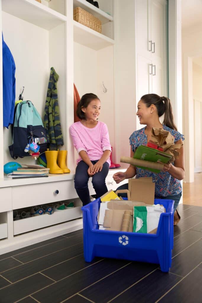 A mom and her daughter placing paper in a recycle bin to illustrate recycling tips