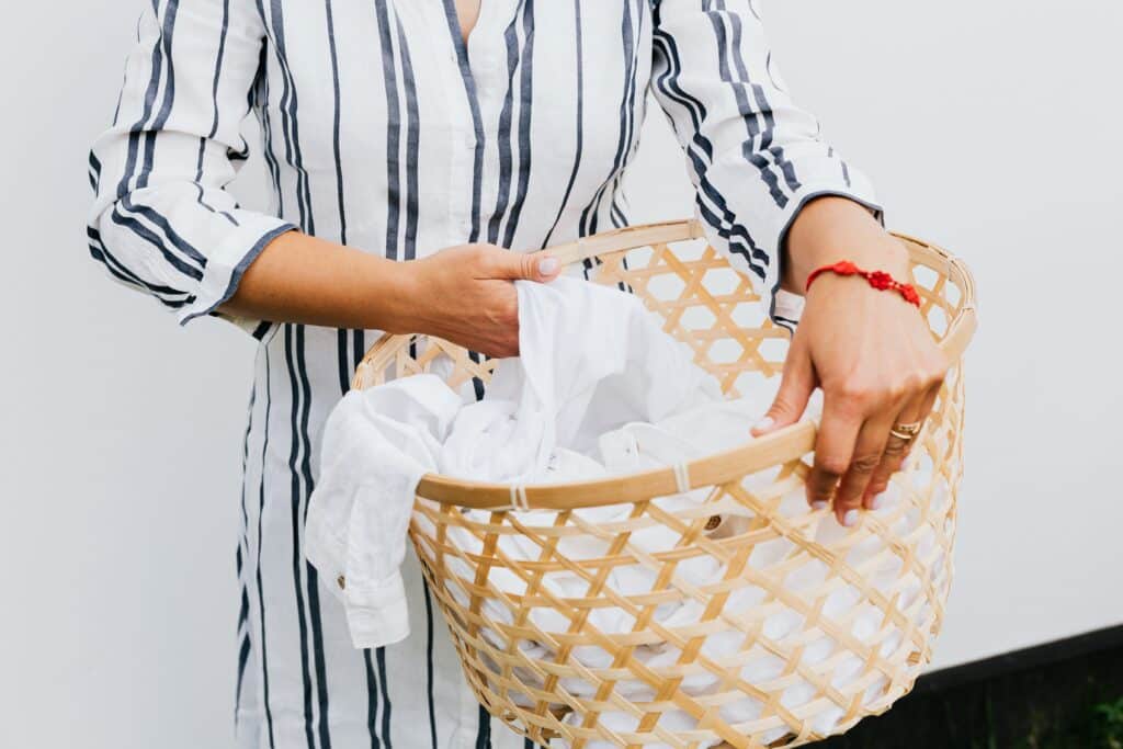 Woman holding a basket of laundry washed with TruEarth laundry strips.