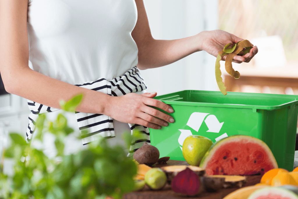 A woman placing compostable items into a countertop compost bin 