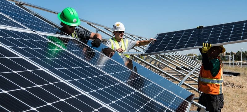 How does solar energy work? Solar workers installing solar panels in a field.