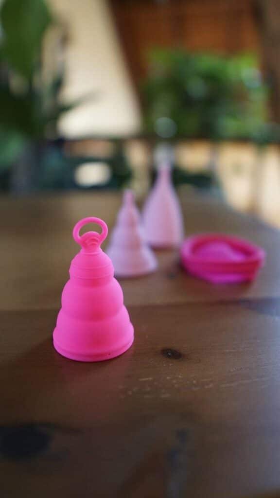 A hot pink menstrual cups in focus with various menstrual cups in the background 