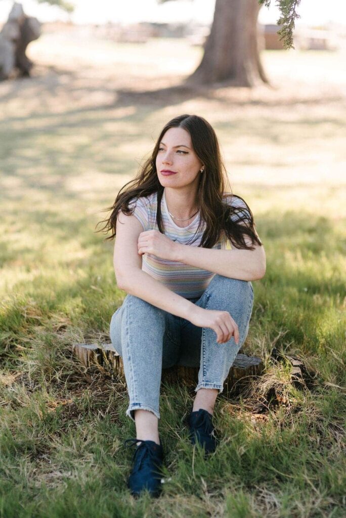 A woman sitting in the grass wearing Wildling barefoot shoes