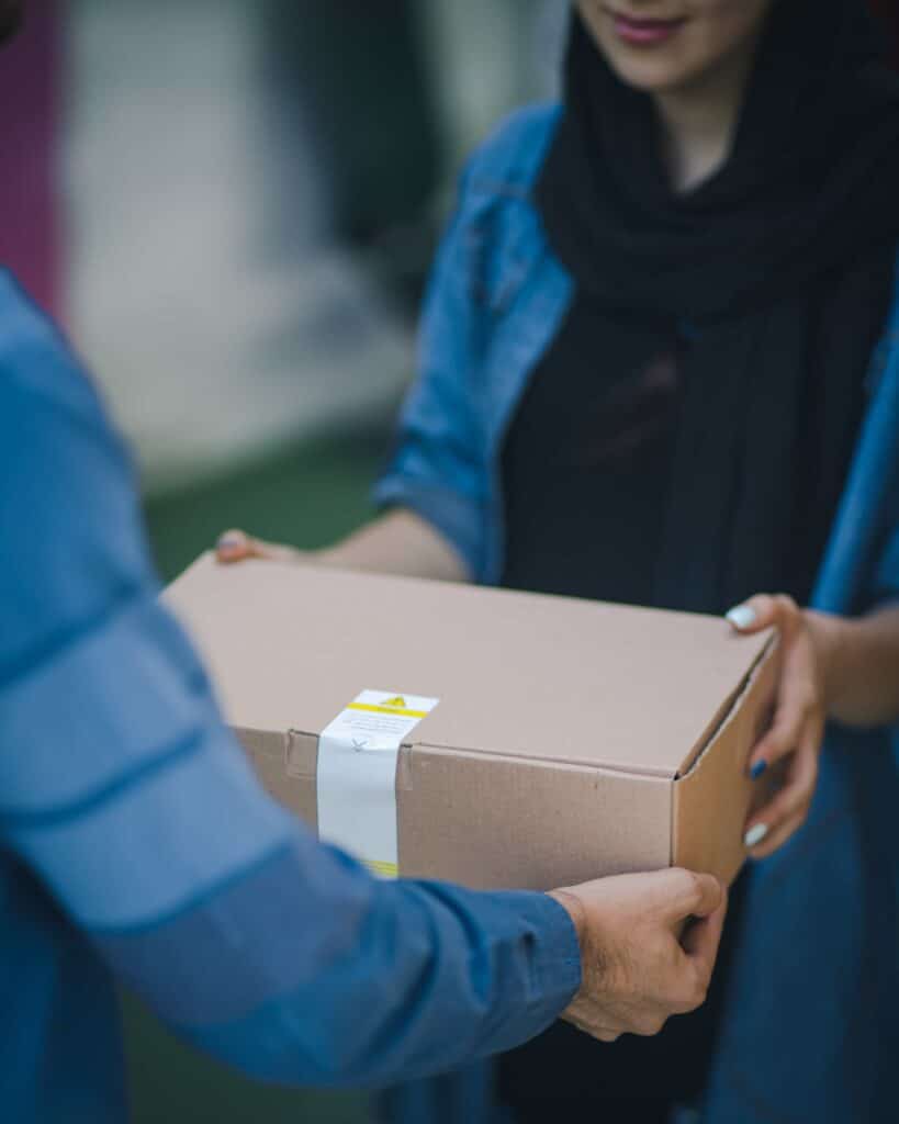 A cardboard box being handed to a woman to illustrate a list of Amazon alternatives