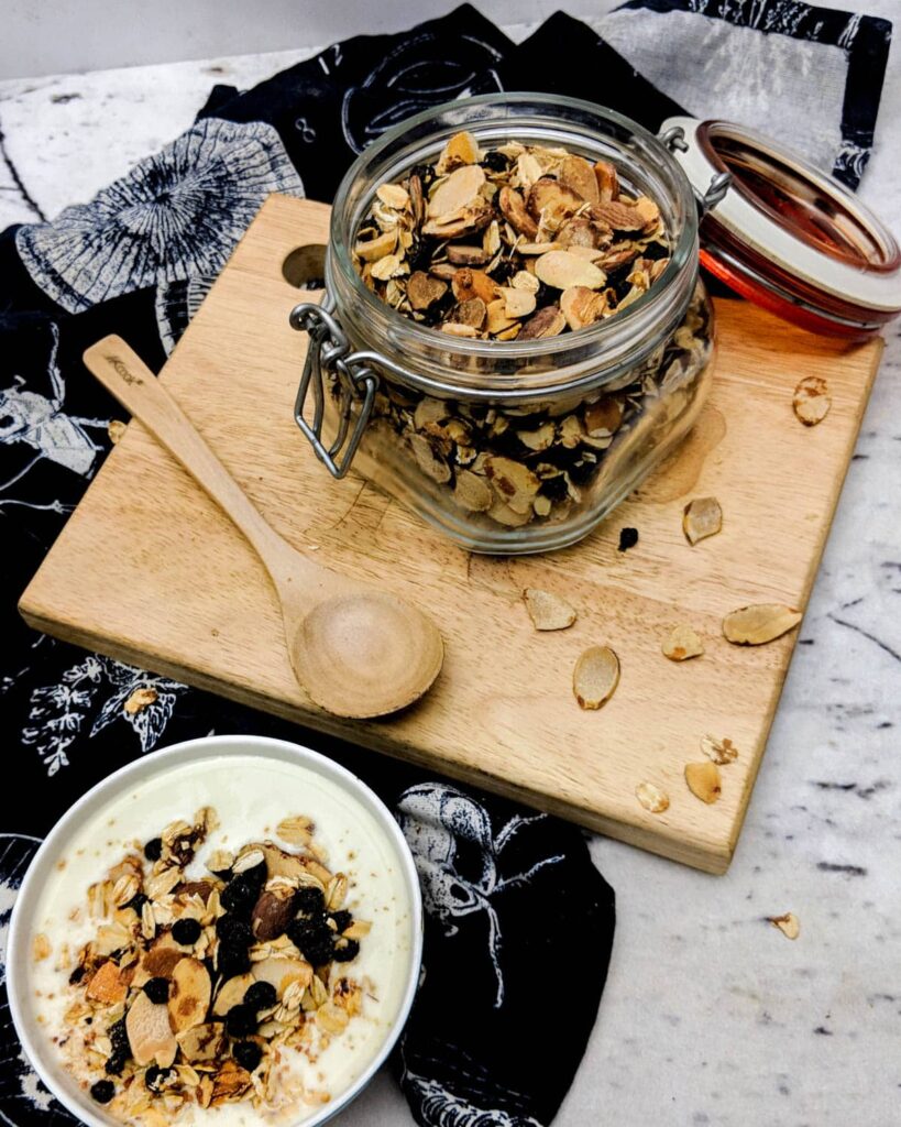 GF granola in a sealable mason jar with a wooden spoon.
